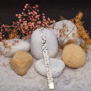 JBRC1020 — THE FACET ARMOUR: Raised, faceted lozenges and white-stone borders create a sculptural bracelet with a strong, repeating surface.